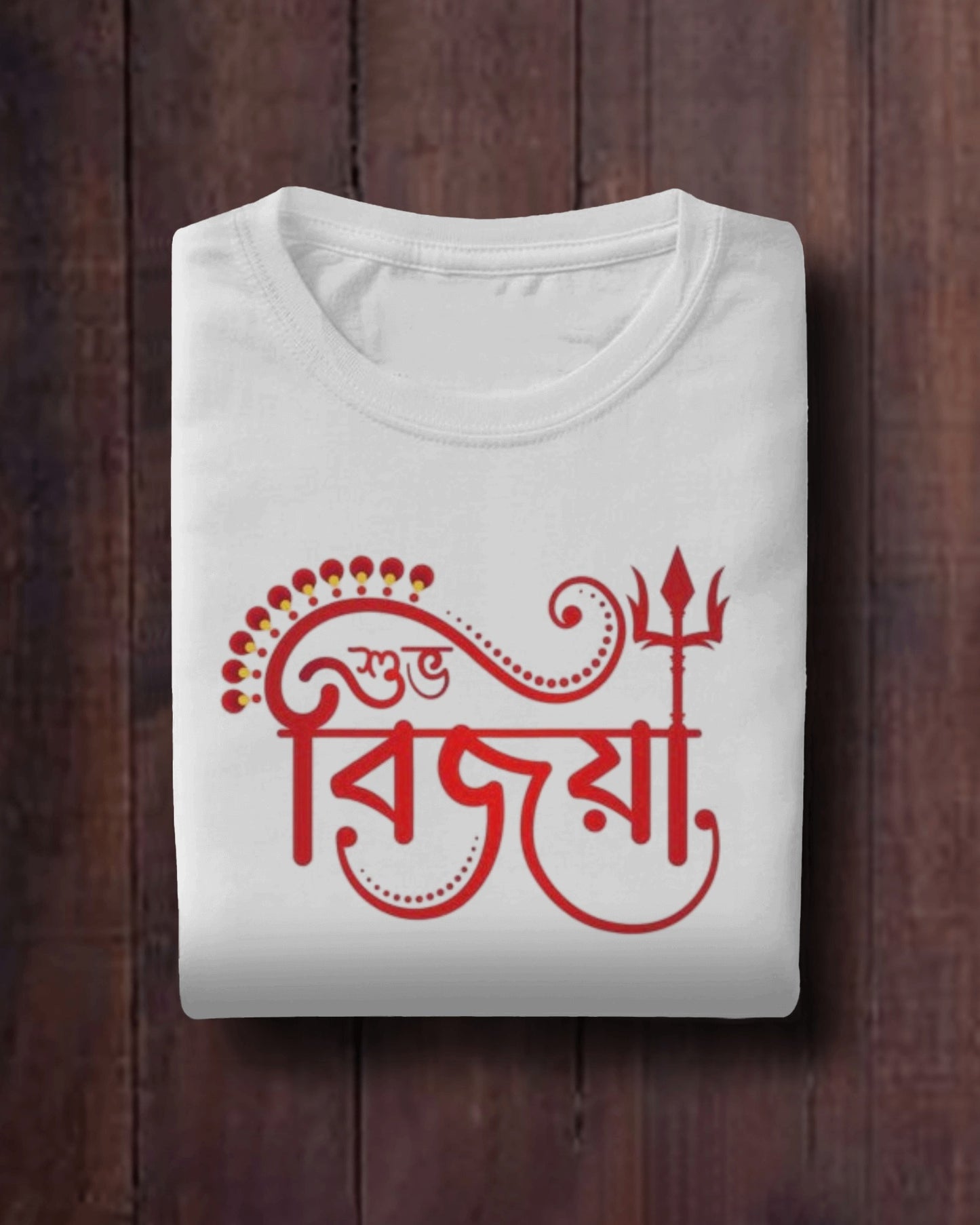 Close-up of Subho Bijoya T-shirt design, featuring Bengali script and trishul symbol on white fabric for Vijaya Dashami.